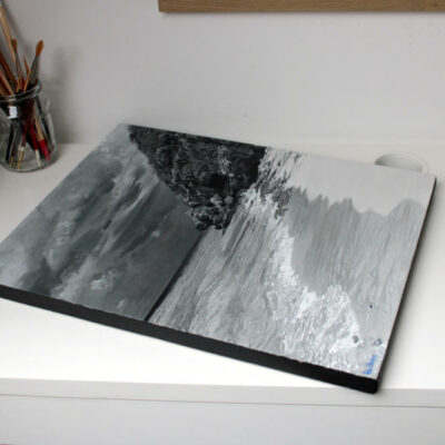Oblique view of the finished monochrome seascape painting, Sapphire by Peter Strobos, on the studio desk.