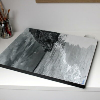 Oblique view of the completed monochrome seascape painting, Sapphire by Peter Strobos, lying flat on a studio desk.